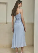 Vestido midi color celeste con diseño evasé, cuello asimétrico de un solo hombro con tirante fino, cuerpo fruncido y cierre de cremallera lateral.