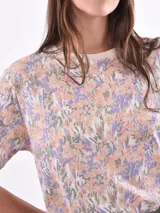 Remera de manga corta color beige con estampado de bananas en tonos amarillo, naranja y rosado.