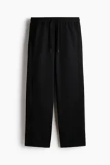 Jogger deportivo de corte relajado y piernas rectas, color negro, confeccionado en tejido funcional con tecnología DryMove. Cuenta con cintura elástica revestida con cordón de ajuste y bolsillos laterales insertados.
