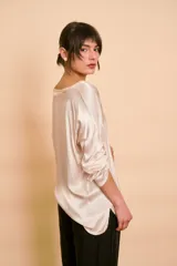 Blusa holgada de satén color beige, con escote en V y mangas largas con trabilla para sujetar remangadas.