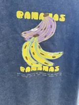 Remera blanca de algodón con estampado de dos bananas y texto.