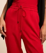 Pantalón de vestir femenino color marrón oscuro, de corte fluido y tiro medio/alto, con cintura elástica ajustable mediante cordón. Presenta bolsillos laterales y cierre frontal.