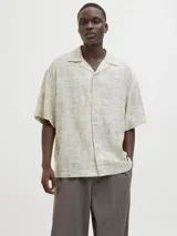 Camisa de manga corta con cuello resort y corte amplio. Confeccionada en tejido plano con estampado geométrico y botánico en tonos neutros.
