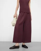 Pantalón palazzo bordó de tejido plisado (crinkle), con cintura elástica y godets centrales en delantero y espalda que aportan amplitud y movimiento.