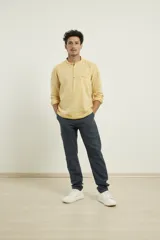 Camisa de lino con cuello mao y cierre frontal parcial con botones. Presenta manga larga y un bolsillo frontal en el pecho.