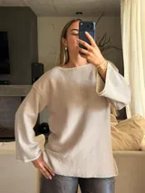 Sweater de tejido de punto jersey en color beige, con silueta oversize, cuello a la base y mangas acampanadas. Presenta terminaciones hechas a mano en crochet a contratono con sutiles detalles de lurex.