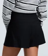 Short de bengalina color negro con cintura estructurada, detalle de botones decorativos y cierre frontal. Presenta un corte evasé que aporta volumen y estructura a la silueta.