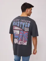 Remera gris de algodón con estampa en la espalda con la inscripción "Surf Island Rustyego" y un diseño de playa con palmeras, olas y tablas de surf.