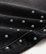 Pantalón de jean super baggy color negro con lavado oscuro y efecto deslavado, con tachas metálicas aplicadas en los laterales de las piernas.