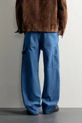 Jeans relaxed fit de mezclilla azul con diseño de bolsillos de carpintero, corte recto y perneras amplias.