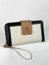 Billetera grande de cuero tricolor: negro, blanco con textura de cocodrilo y marrón claro. Tiene cierre de cremallera, correa de mano y botón de cierre con logo de búho.