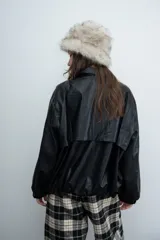 Chaqueta de cuero sintético color marrón con capucha y solapas amplias en tela escocesa a cuadros. Posee cierre frontal, puños elásticos y diseño de corte holgado.