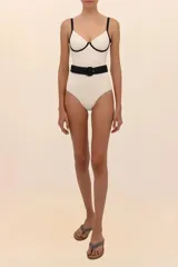Traje de baño entero blanco con breteles finos negros, escote corazón con borde negro y cinturón negro con hebilla redonda.