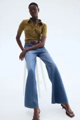 Top de punto color verde oliva, ajustado al cuerpo, con cuello camisero, tapeta de botones y costuras decorativas verticales en el frente.