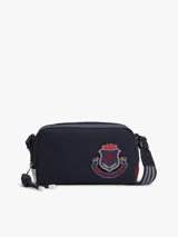 Cartera tipo camera bag Tommy Hilfiger de color azul marino, con compartimento principal con cierre, correa ajustable y desmontable, y parche con el logo de escudo de la marca bordado en el frente.