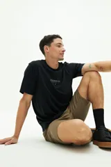 Remera de manga corta color negro, con cuello redondo y diseño de arte estampado pequeño en el centro del pecho.