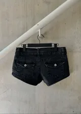 Micro short de jean negro de tiro bajo, con bolsillos traseros con solapa y botones.