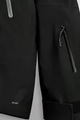 Cazadora deportiva de esquí en color negro, confeccionada en tejido técnico impermeable de tres capas con costuras y cremalleras termoselladas. Cuenta con capucha ajustable, ventilación en axilas, puños con ajuste de tira adherente y puño interior elástico con abertura para el pulgar. Incluye sistema de rescate RECCO y faldón interior para protección contra el frío.