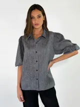 Camisa de lino color beige, con mangas abullonadas tres cuartos y cierre frontal de botones.