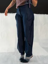 Pantalón babucha de denim azul, con corte a la cintura baja y diseño tipo origami. Presenta pliegues y costuras que favorecen la silueta. Creado y producido en Uruguay.