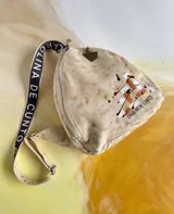 Mochila de cuero natural con efecto desgastado, diseño pintado a mano de Carolina De Cunto, correa ajustable en negro con inscripciones y cierre de cremallera.