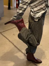 Bota de estilo western color bordó, con diseño de costuras decorativas en relieve y taco cuadrado. Presenta una terminación brillante y punta ligeramente cuadrada.
