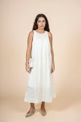 Vestido midi color crema, de corte recto y cuello redondo. Presenta bolsillos laterales y diseño sin mangas.