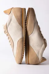 Championes urbanos de diseño retro, confeccionados en una combinación de gamuza y cuero texturizado en tonos beige y arena. Presentan cordones al tono y una suela dentada de goma en color caramelo.