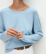 Suéter de punto color marrón chocolate, con cuello redondo y mangas largas con puños acanalados. Presenta un diseño básico y versátil de corte recto.