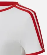 Remera blanca de algodón con estampa frontal de Mickey Mouse y detalles en color rojo en cuello y mangas. Presenta un diseño ajustado con líneas laterales en las mangas.