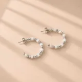 Aros tipo argolla abierta de plata 925, decorados con cuentas redondas metálicas intercaladas con cuentas cúbicas blancas.