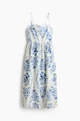Vestido midi de tejido liviano color blanco con estampado floral en tonos azules, escote cuadrado, breteles finos y falda con vuelo.