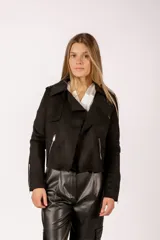 Chaqueta tipo biker de gamuza sintética en color negro, con cierre frontal asimétrico, bolsillos laterales con cierre y detalles de cierres en los puños.