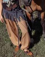 Accesorio de cuero vacuno con diseño triangular y flecos largos, diseñado para llevarse sobre los hombros o cruzado al cuerpo. Presenta un estilo western con tiras largas para anudar.