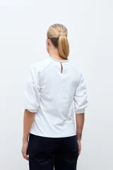 Remera blanca de manga tres cuartos con detalles de bordado calado en el frente y en los hombros, con cuello redondo y puños elásticos.