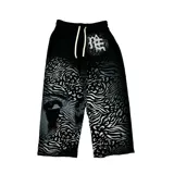Pantalón negro de algodón con diseño estampado de animal print en degradé y un rostro oculto, con cordón ajustable en la cintura y corte recto.