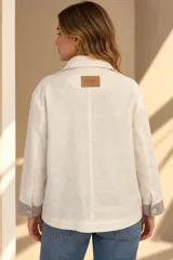 Campera marrón de lino con diseño bicolor, con una franja central gris claro que incluye botones de nácar. Cuenta con cuello alto, mangas largas con puños grises, bolsillos frontales aplicados y silueta amplia.