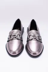 Mocasines de cuero en tono bronce metalizado, con detalle de aplique metálico dorado en el empeine y taco cuadrado bajo de madera.