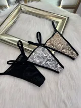 Pack de tres microtangas de encaje con diseño floral, cuentan con tiras laterales regulables y bordes con terminación en cinta elástica. El set incluye una prenda negra, una blanca con estampado floral negro y una beige con estampado floral negro.