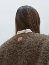 Chaleco color crema con textura de piel sintética, sin mangas y con forro interno.