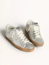 Zapatilla Golden Goose modelo Super-Star color plateado con estrella lateral y suela marrón.