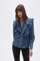 Camisa de jean azul con volados grandes en el frente, escote en V y cierre frontal con botones plateados.