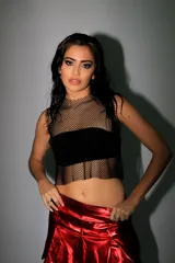 Top corto de red negra con strass, corte crop y cuello alto. Presenta una banda horizontal opaca a la altura del busto.