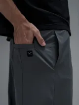 Pantalón cargo de corte oversize confeccionado en microfibra técnica. Presenta cintura elástica, bolsillos laterales y un bolsillo cargo con cierre de broche snap. Incluye un sistema de elásticos con tancas en los tobillos para regular la apertura y la silueta.
