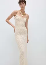 Vestido largo de tejido de punto fino con diseño entallado, tirantes finos y cuello escotado. Presenta detalles calados en toda la prenda y terminaciones con volantes en el escote.