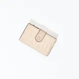Billetera pequeña color beige con diseño acolchado en forma de rombos y cierre con broche a presión. Incluye cierre superior con cremallera y múltiples compartimentos internos para tarjetas y billetes.