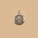 Medalla circular de plata 925 con relieve de San Cristóbal cargando al niño Jesús, con acabado pulido en los bordes y oxidado en el centro.