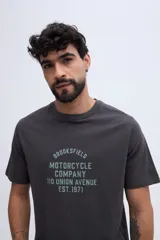 Remera blanca de manga corta con cuello redondo y estampa frontal de estilo vintage con texto inscripto.