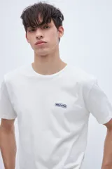 Remera blanca de manga corta con cuello redondo y logo estampado en el pecho.