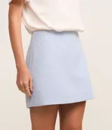 Short pollera de tiro medio confeccionado en tejido tweed texturizado color celeste. Presenta un diseño corto con cintura fija y cierre lateral con cremallera.